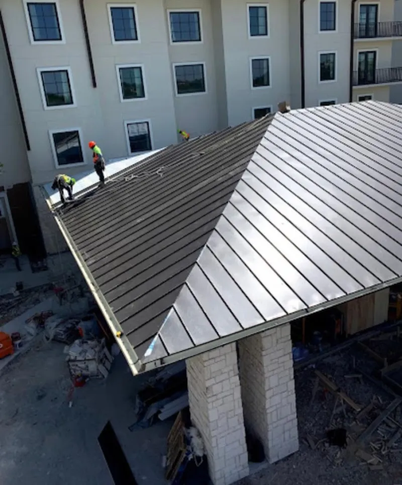 Crew installing standing seam metal roof panels on a commercial project in Rockport